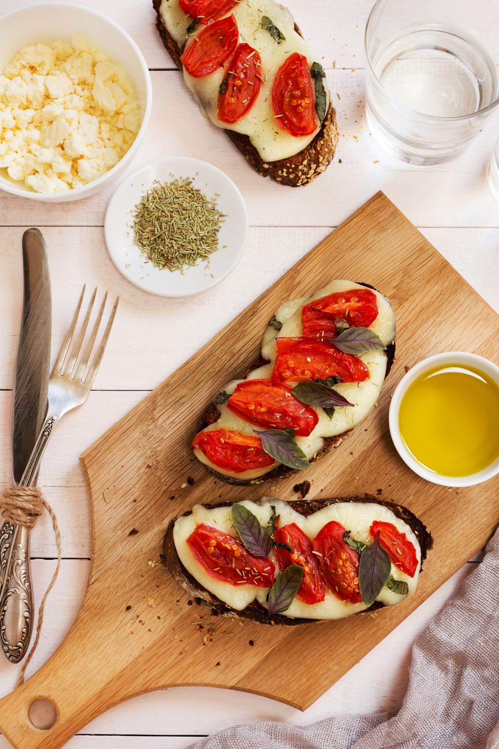 a wooden cutting board topped with slices of bread covered in toppings