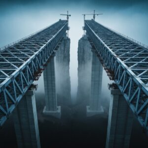 A highly detailed, cinematic shot of a massive, unfinished bridge over a foggy chasm. The bridge is 90% complete, but a sheer, daunting gap remains before the other side. High contrast, architectural photography, moody lighting, symbolizing the 'Last Mile Penalty'.
