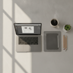 A photorealistic, top-down view of a modern minimalist digital workspace, featuring a sleek laptop displaying clean document layout software, a modern tablet, organized ceramic coffee cup, warm natural morning window light, high-end design aesthetic, no text, no logos.