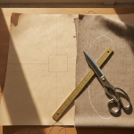 A close-up overhead flat lay of a tailor's cutting table with a crisp printed paper sewing pattern, an engraved brass tailor's ruler measuring a printed calibration square, chalk marks on pure wool fabric, and steel shears.